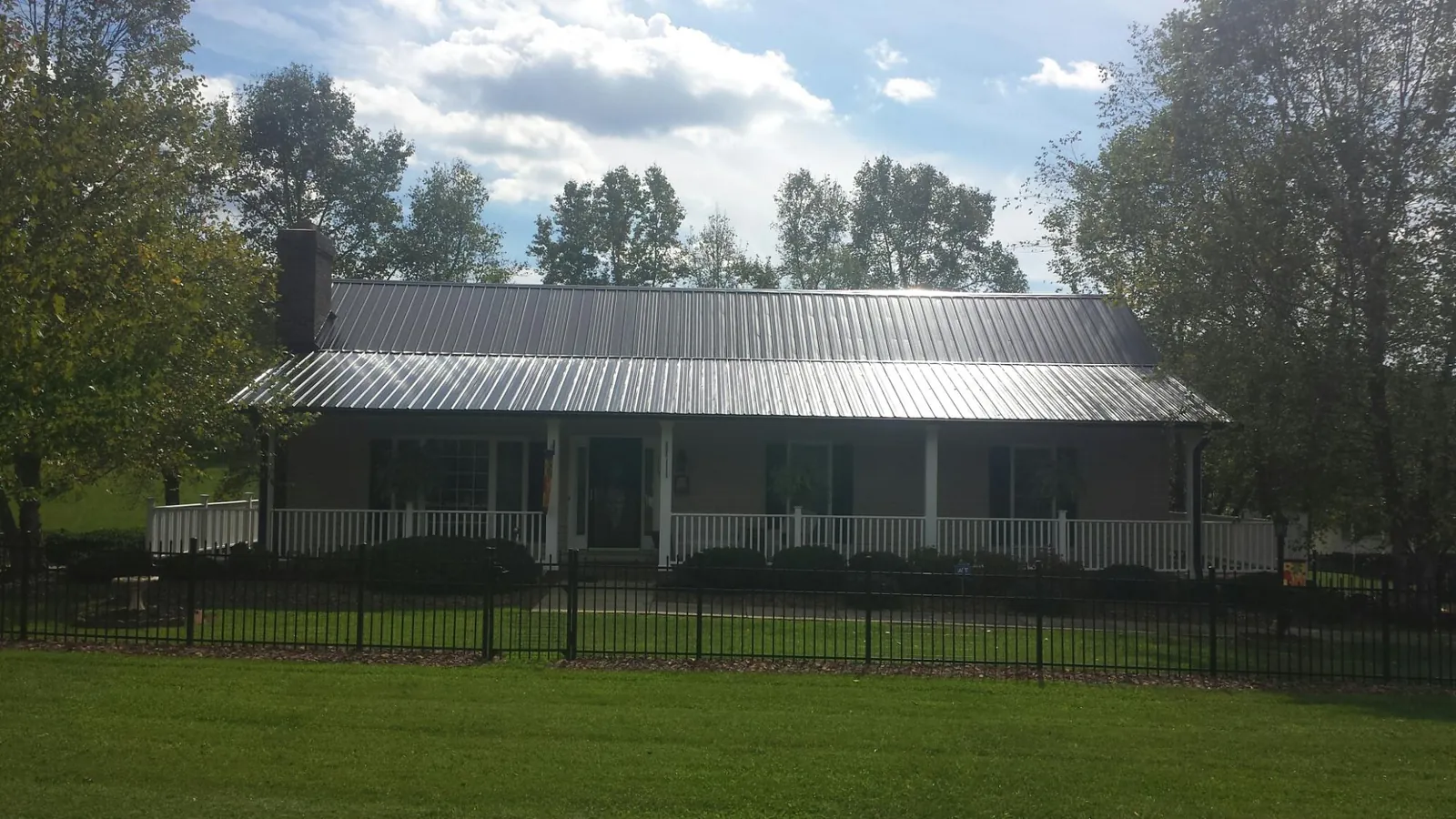 Gray metal roof on a brick ranch with a full width front porch — Gutter Guard Installation work by our crew in Gardena