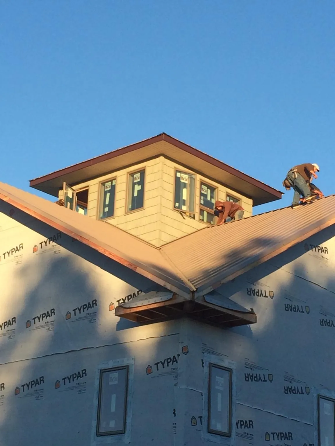 Roofers working around a rooftop cupola on a new metal roof at sunset — Roof Waterproofing in Gardena by Roofing Brothers